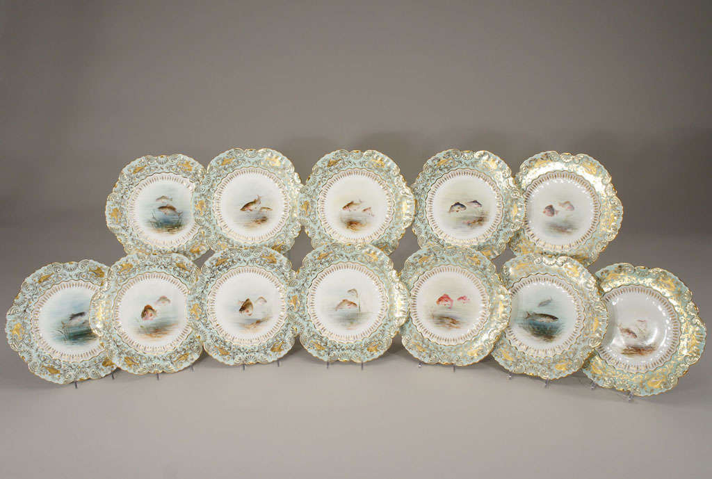 This amazing set of 12 hand painted, artist signed fish plates with scalloped borders and beautifully painted figural fish, are bordered by a soft seafoam green enamel 