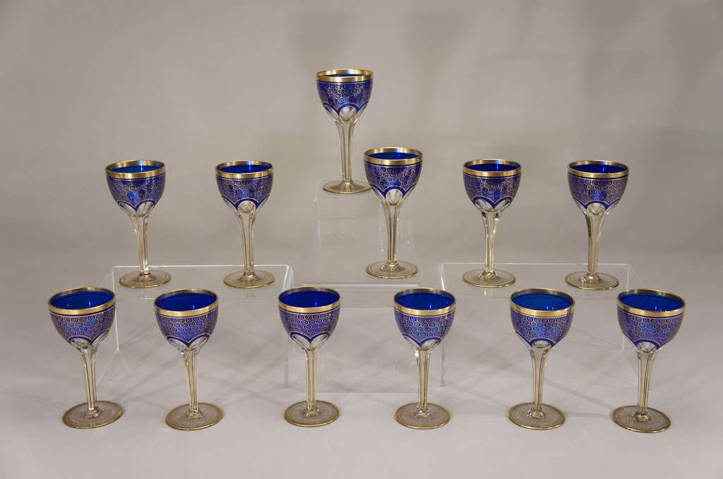 A lovely set of 12 hand blown crystal goblets with cobalt overlay, cut to clear with panel cutting and facet cut stems. The bowl is beautifully decorated with hand painted swirled gold enamel, as is the foot and rim. Large and practical, these stand