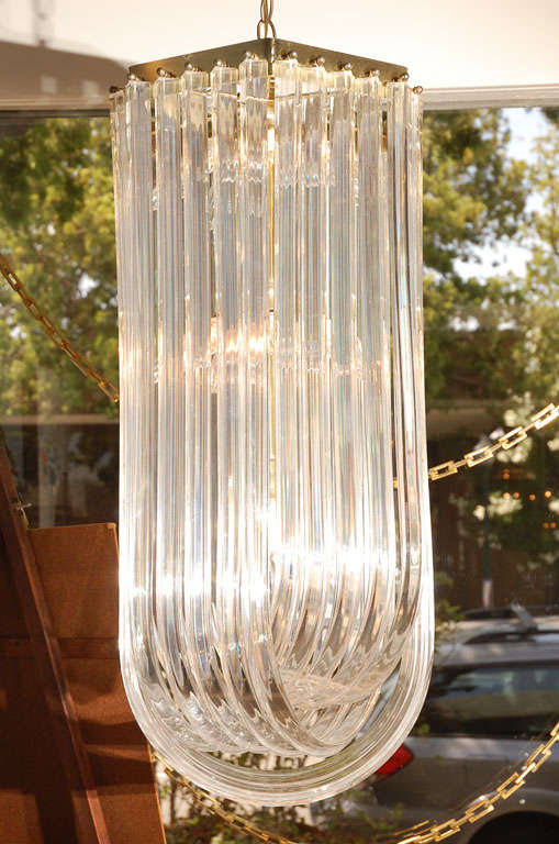1970s chandelier featuring 3 tiers of ribbon Lucite with a brass hexagon frame.