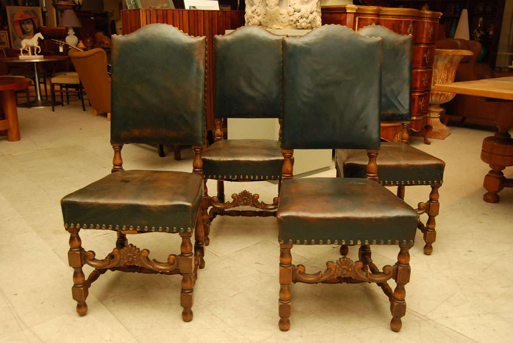 Handsome set of eight dining chairs in oak, legs turned with carved oak stretchers, covered in dark blue/green leather upholstered with large brass studs.