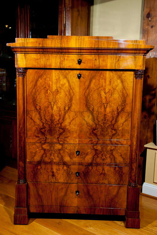 A beautiful early 19th century Biedermeier Secretaire with bookmatched veneer on pine.  This piece is comprised of two free-standing corinthian capitals supporting a frieze drawer with a fall front door below and three large drawers simply adorned
