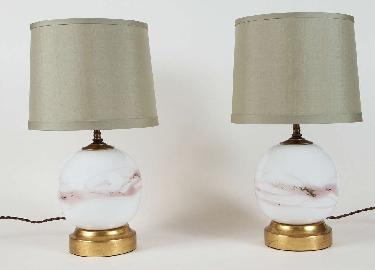 Pair of vintage round Holmegaard handblown opaque white glass table lamps with light mauve or pink marbled detailing. Designed by Michael Bang for Danish glass manufacturer Holmegaard. Bang has worked for Holmegaard since 1968. Features a 22-karat