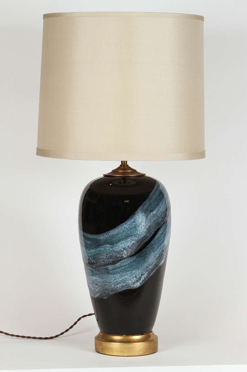 Vintage black ceramic lamps with book matched blue drip glaze design. Features a 22k gold gilt base, adjustable double cluster sockets, and twisted brown silk wrapped cord. Custom taupe pongee silk shades included. Newly wired.