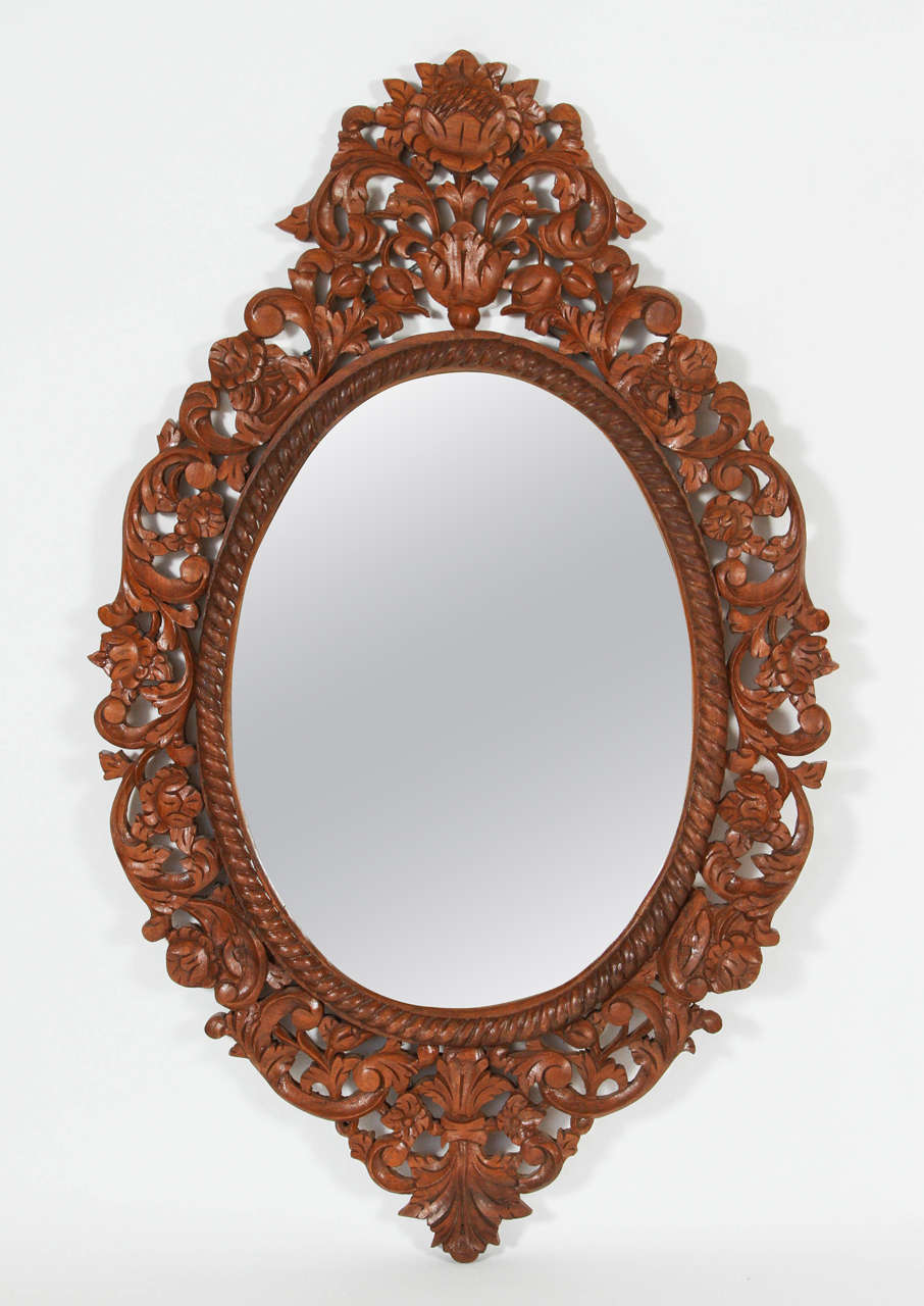 Carved teakwood mirror frame with floral inspired pattern. New oval mirror and wire on back for hanging.