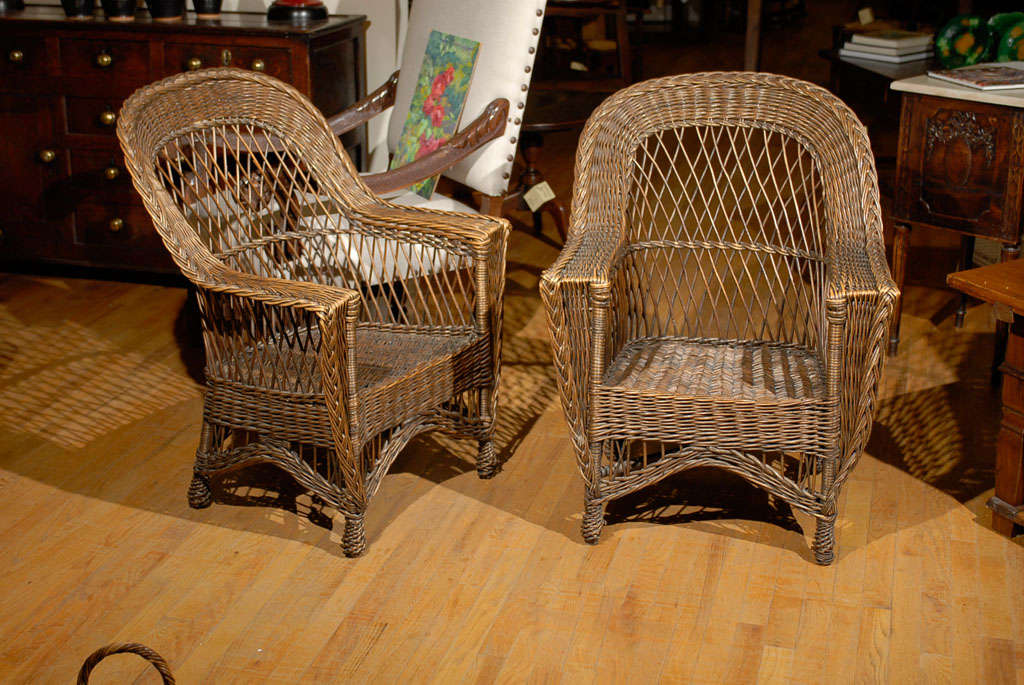 This is a handsome pair of wicker chairs.  The style is Bar Harbor which is known for the open weave and braid framing the piece.  The feet are in the pineapple style.  These chairs are natural.  Not painted.  It is rare to find American wicker that