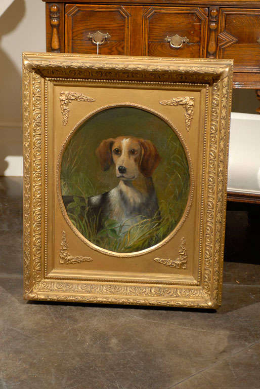 A 19th century English oil painting of a sporting dog in a rectangular gilt wooden frame. The artist has captured this alert half-length Beagle in the tallgrass, with the soft pleading expression of his shining hazel eyes, as if just stopped,