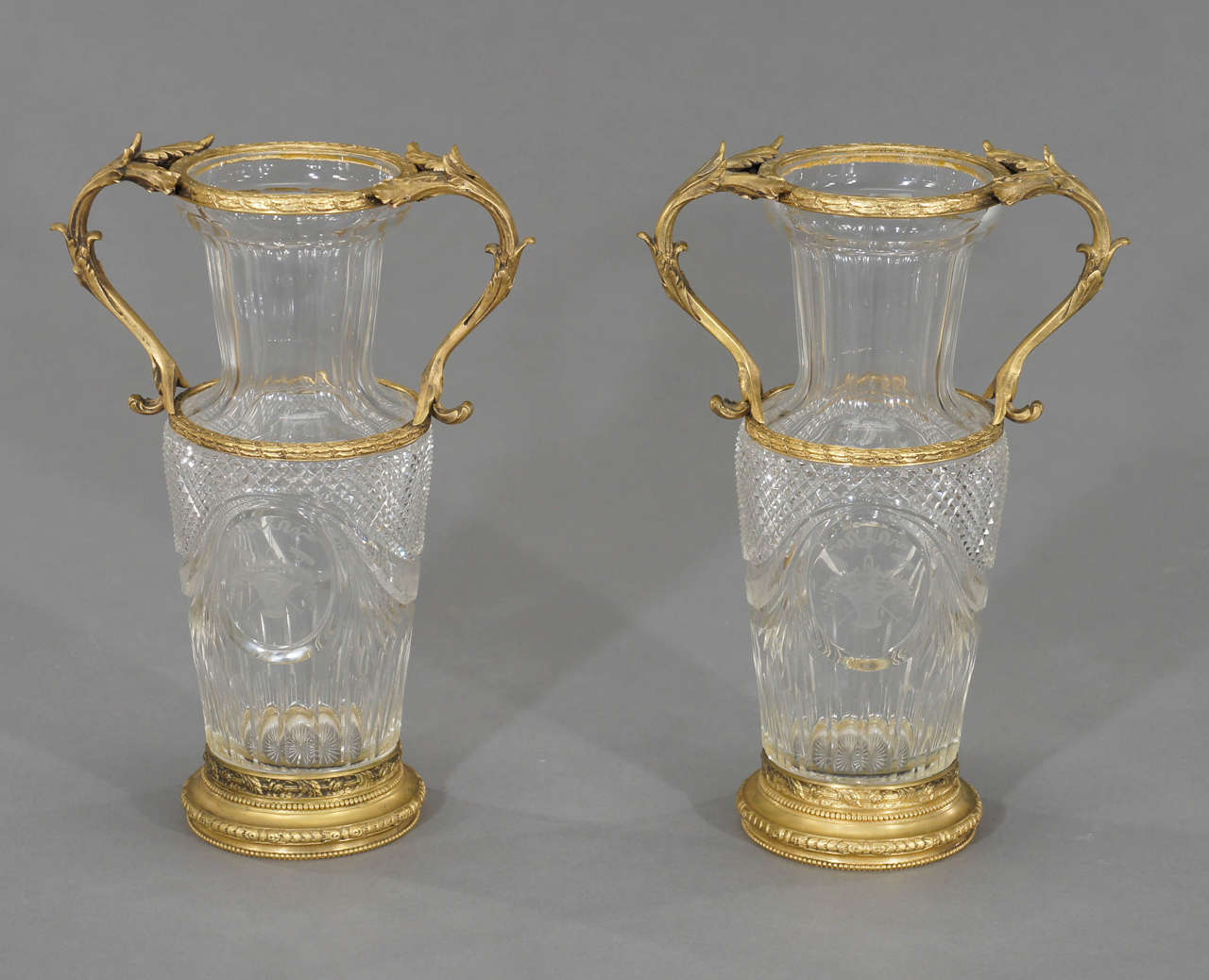 This is  a more unusual pair of Baccarat crystal vases in gorgeous vermeil bronze mounts. They are not the typical molded crystal, these are hand blown and finely cut with diamond point cutting and detailed copper wheel intaglio engraving, depicting