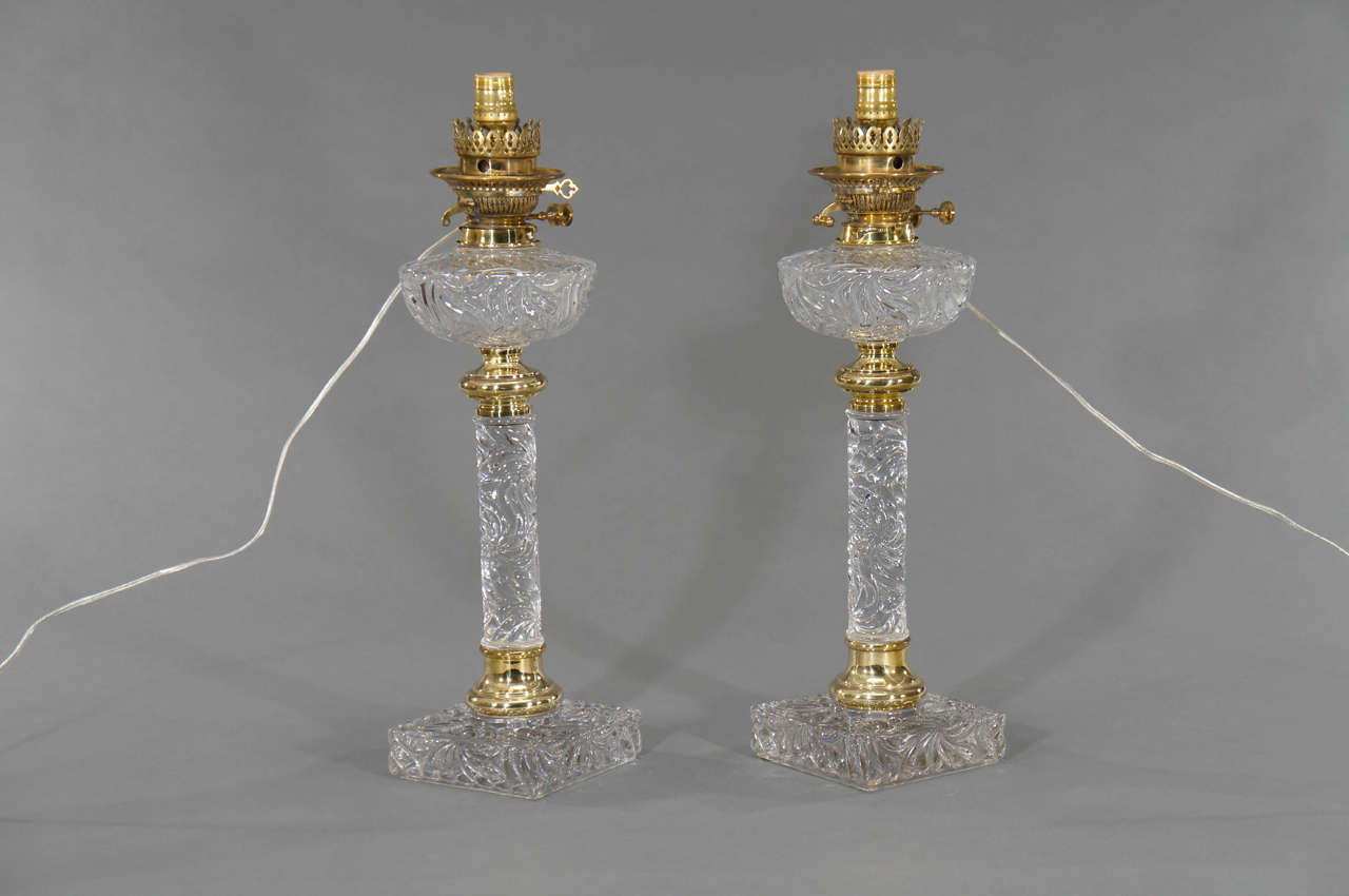 An original pair of Baccarat crystal lamp bases with molded crystal and original brass fonts and trim. The heavy square footed bases maintain the weight and balance to this incredible pair of lamps. The rare pattern of continuous swirled crystal,