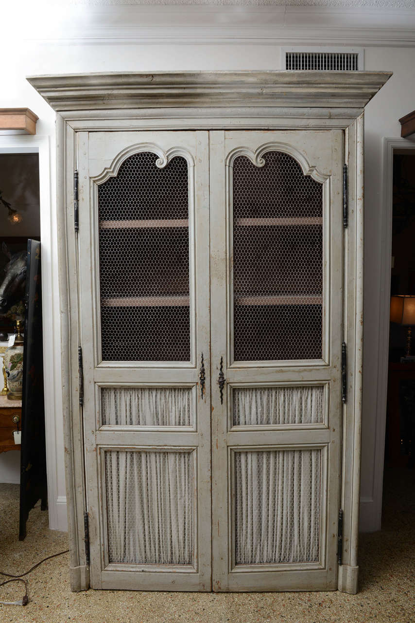 A handsome cabinet with a antique finish which is suitable to bend with other painted furniture or wood tones.  Each of he pair of doors is divided into three sections & mounted with wire because of this , you may use portion(s) for storage, as