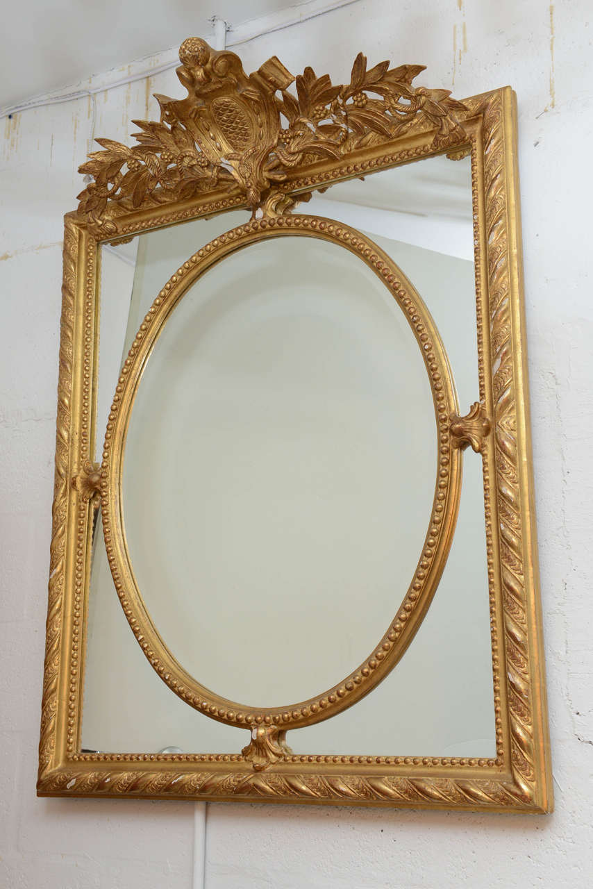 Unique design & well executed, this mirror is all hand carved with appliques over the mirror & protruding crown so that it is able to hang in front of a crown molding.  Original restored finish
