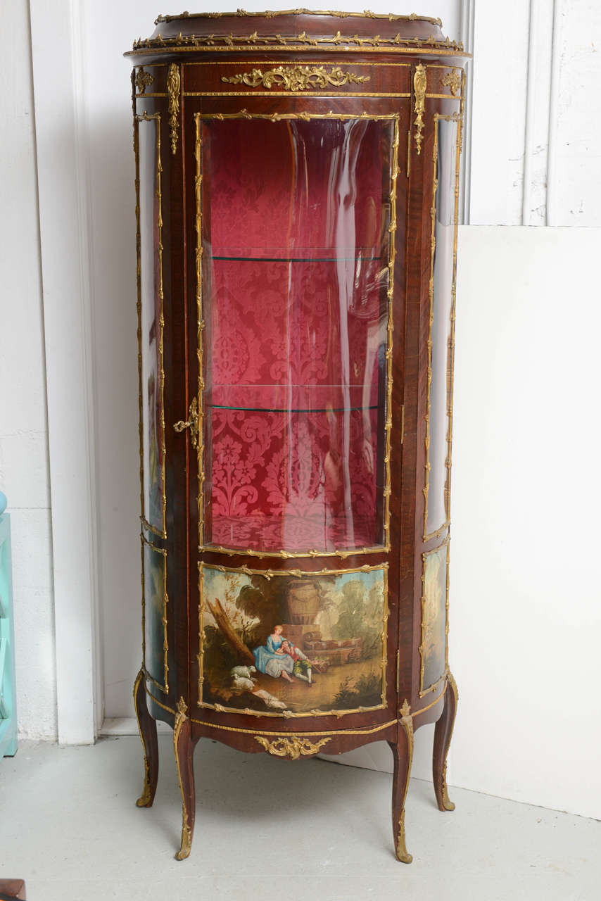An oval curved glass vitrine or curio display cabinet has the renowned 