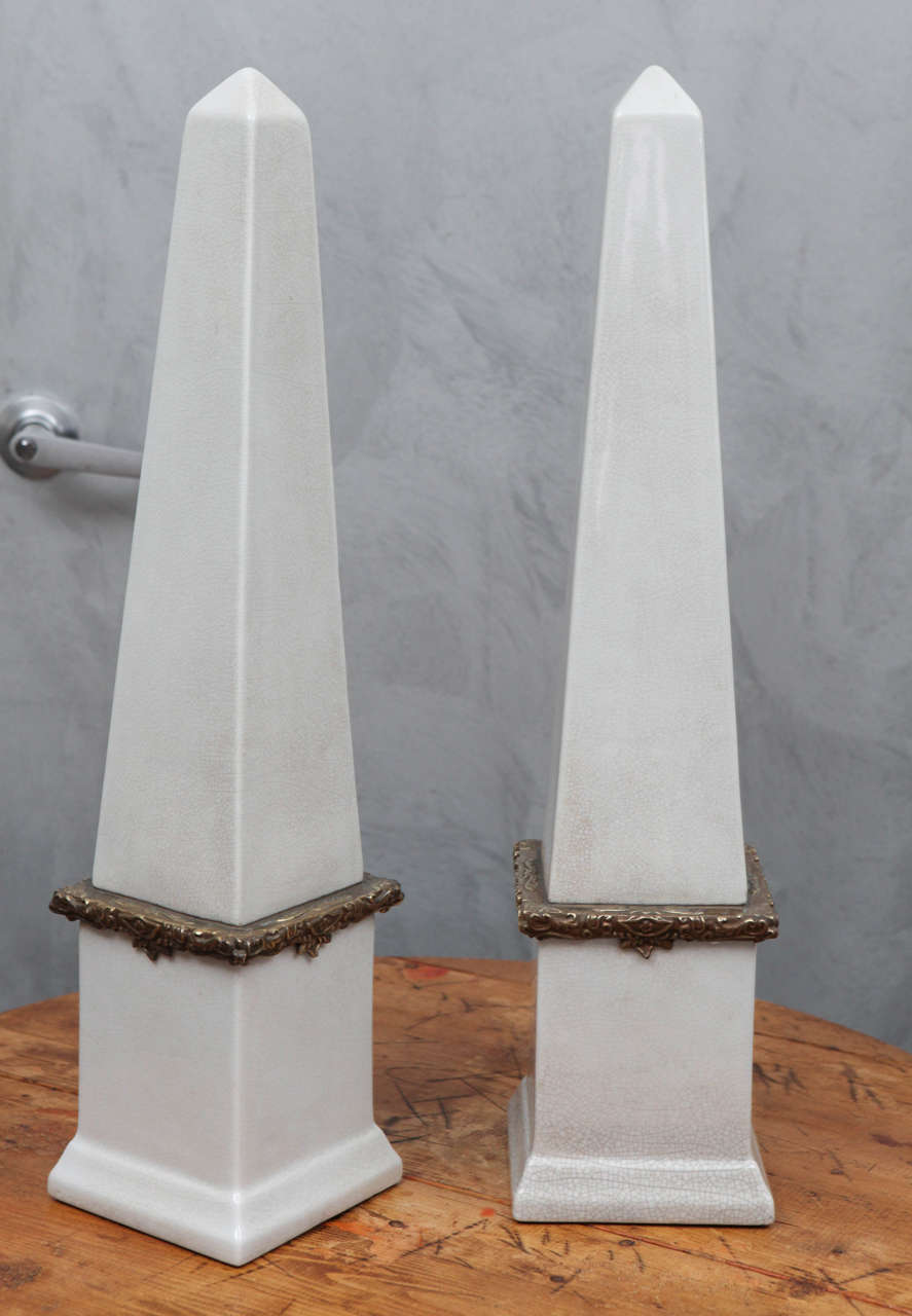 These beautifully made ceramic obelisks are over two feet tall and make a great impression in any setting. With a subtle crazed glaze, these pieces have a real special quality including the caste floral and fauna decorative details in the bronze