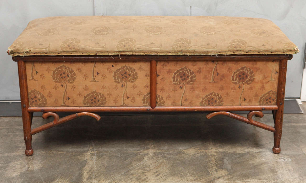 This is a beautifully upholstered bentwood bench that opens to be used as a trunk. The piece has very solid construction with exposed bentwood framework, turned ball feet and curved support stretchers. This original antique treasure has faded and