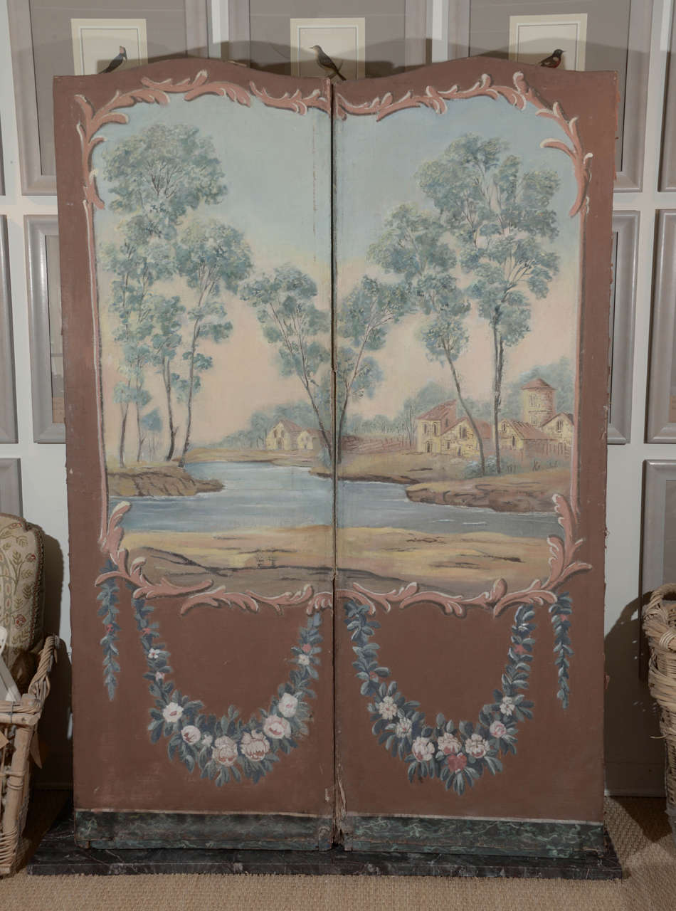 This pair of antique Paravents are coordinating screens. Beautifully painted with provincial river scenes, floral swags and a decorative botanical motif on the back. They are gorgeous, facing in either direction. They can be used as a room divider,