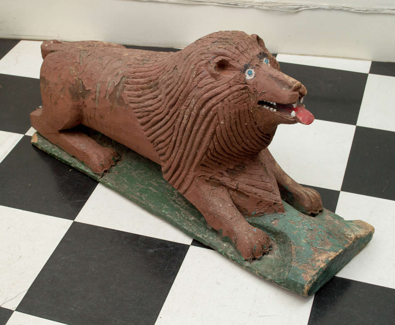 20th century American folk art carved lion in a seated position.  Old weathered  textured finish and paint. Carved from a small log. Tail repaired.