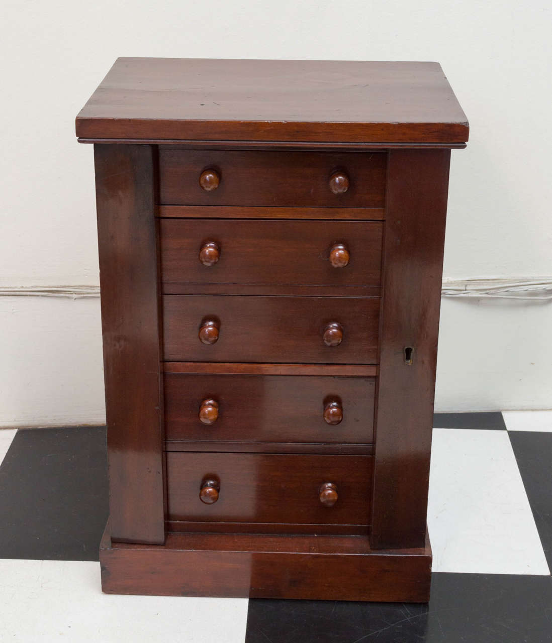 19th c. English mahogany miniature collector's chest with lock side flaps. Five graduated drawers and a plinth base. Brass locks and a steel key.