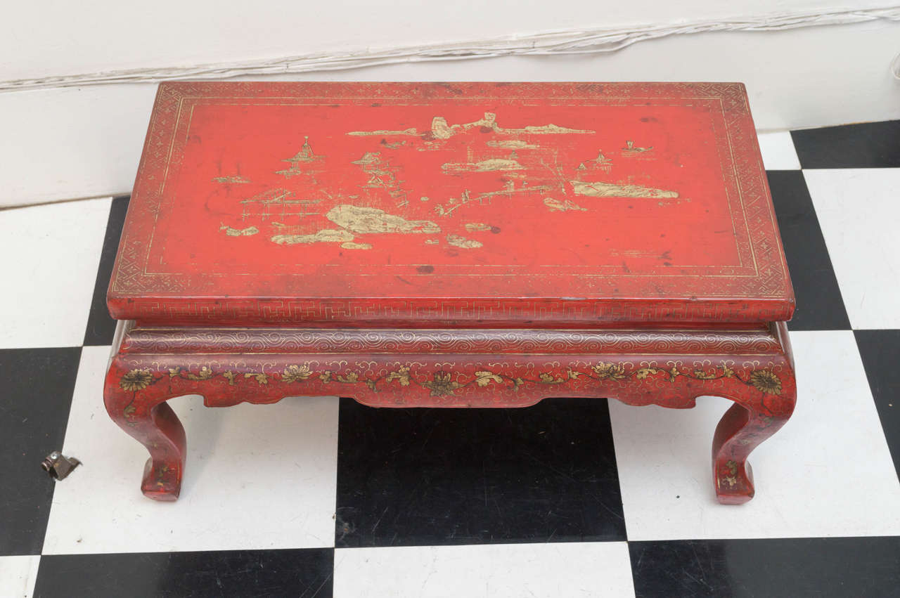 20th century Chinese Kang table with red lacquer and gilt decoration. Hand painted. Landscape motif top with floral and vine decorated edges. Good shaped legs. Old 
