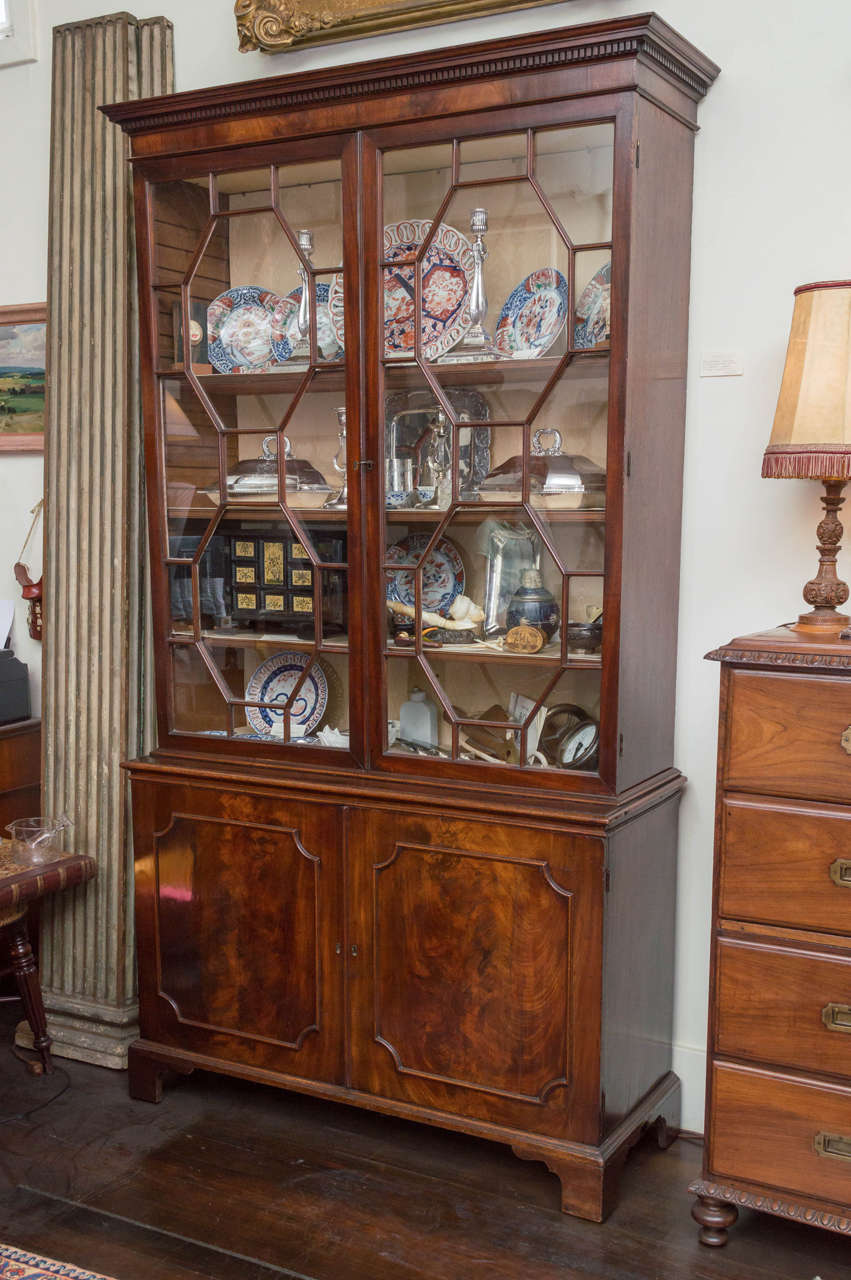 English George III figured mahogany bookcase. Excellent scale with original glass, locks and feet. Old surface of deep color. Glazed cabinet on top over two-drawer base (2 parts). Adjusting shelves top and bottom. Original glazing, moldings and