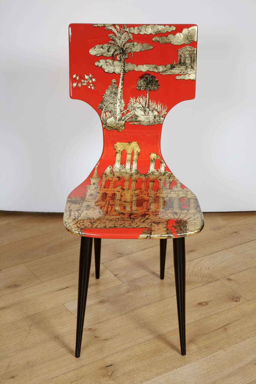 Current production, cinnabar lacquered chair, with transfer printed design of architectural settings taken from the 'antique', tropical and Eastern landscapes, finished in gold leaf, on black lacquered legs
Fornasetti mark, with hand written number