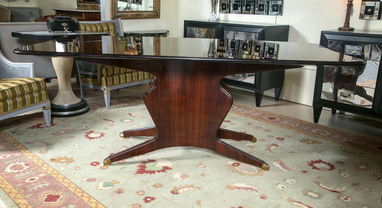 A fine custom quality dining or conference table by Osvaldo Borsani. Bearing makers label on the reverse of the table top and dated 1960. The vase form pedestal base on brass casters of solid rosewood construction supporting the original wooden