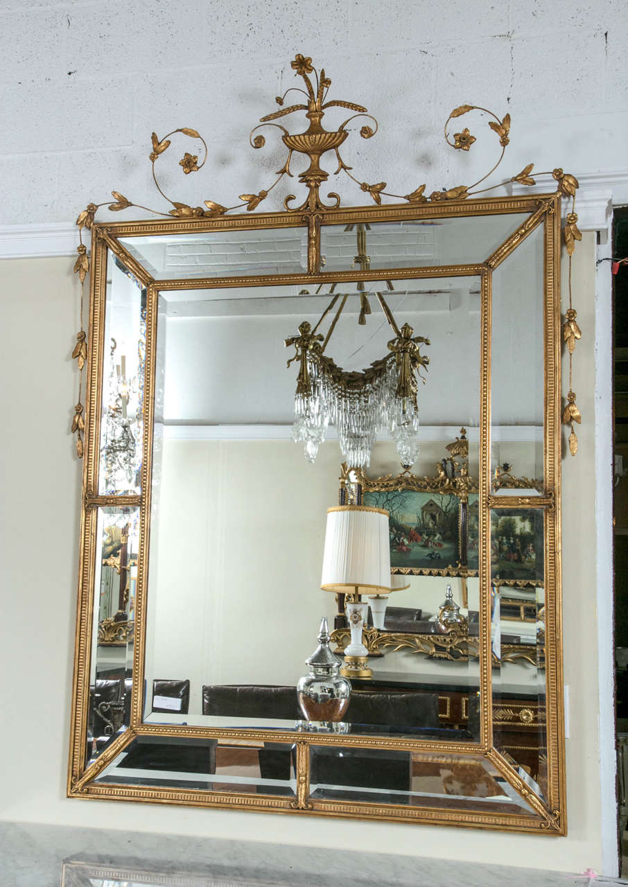 A pair of monumental Louis XVI style giltwood mirrors. The center mirrors framed with beads and fleur-de-lis leading to a floral crest. The magnitude is stunning yet subtle. Fit for a castle! The center beveled mirror panel is framed with a gilt