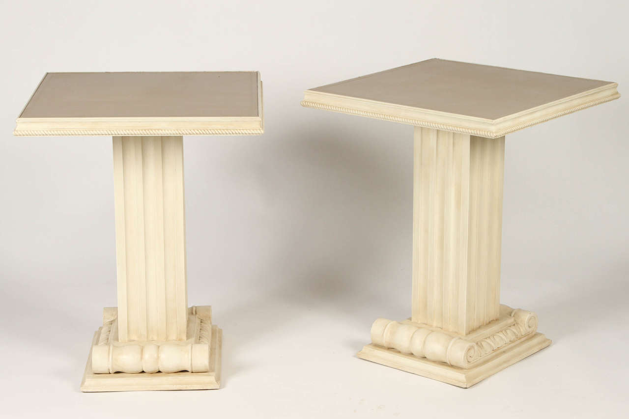 A pair of cream-painted columnar form side tables with leather-inset tops. 
Modern, but with a Classic feel. These neutral tables would work well flanking a sofa to hold a lamp, an arrangement of fresh flowers, or a stack of your favourite books.