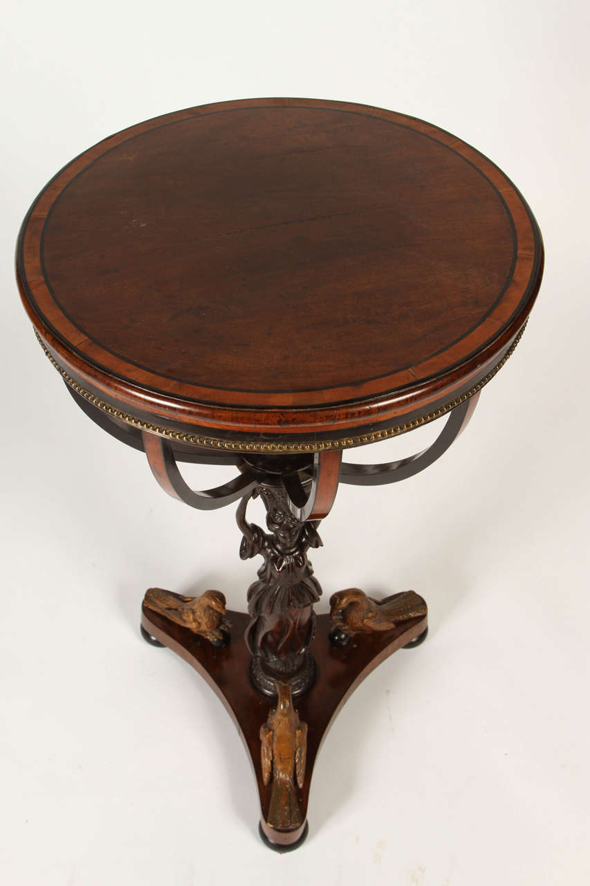 This is an truly unique parcel-gilt and ebonized Mahogany work table. Circa 1810, probably Viennese, the top formerly hinged with a lined basket interior underneath supported by a classically-draped woman holding aloft a leafy basket. The later