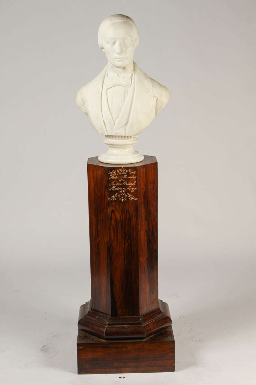 This wonderful carved marble portrait bust of Antonio Orlandi (1834-1856) sits upon a rosewood pedestal. Dated 1857. 
Signed Ant. nio Busciolano faceoa, 1857; the octagonal pedestal inscribed Nato. o 25 Dicembre, 1834, Antonio Orlandi, Morto a 18