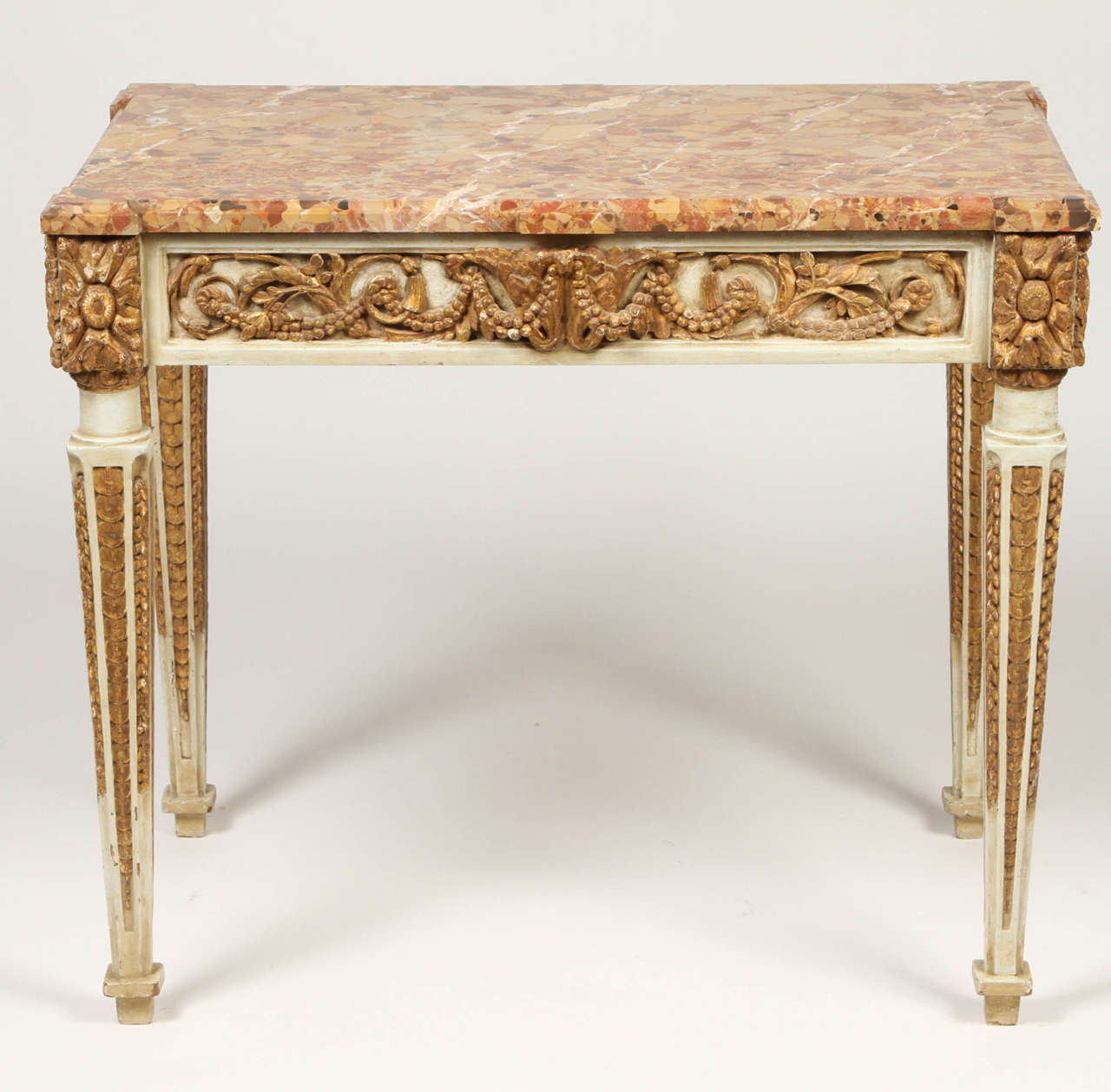Wonderful Italian console table from the late 18th century that has been heavily carved with winding foliated scrolls and acanthus leaves. The finely tapered and reeded legs are carved with great detail and topped with cornered rosettes. The gilt