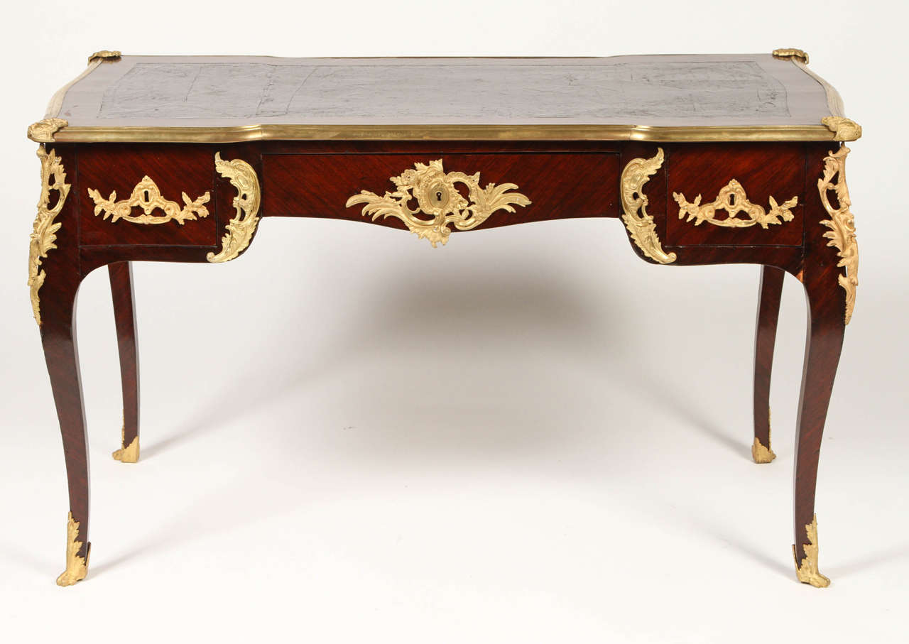 Spectacular French writing table from the fourth quarter of the 19th century. Ornate gilt bronze mounts and cabriole legs. The original leather inset top bordered by bronze molding with four corners in gilt bronze mounts Waved apron with three