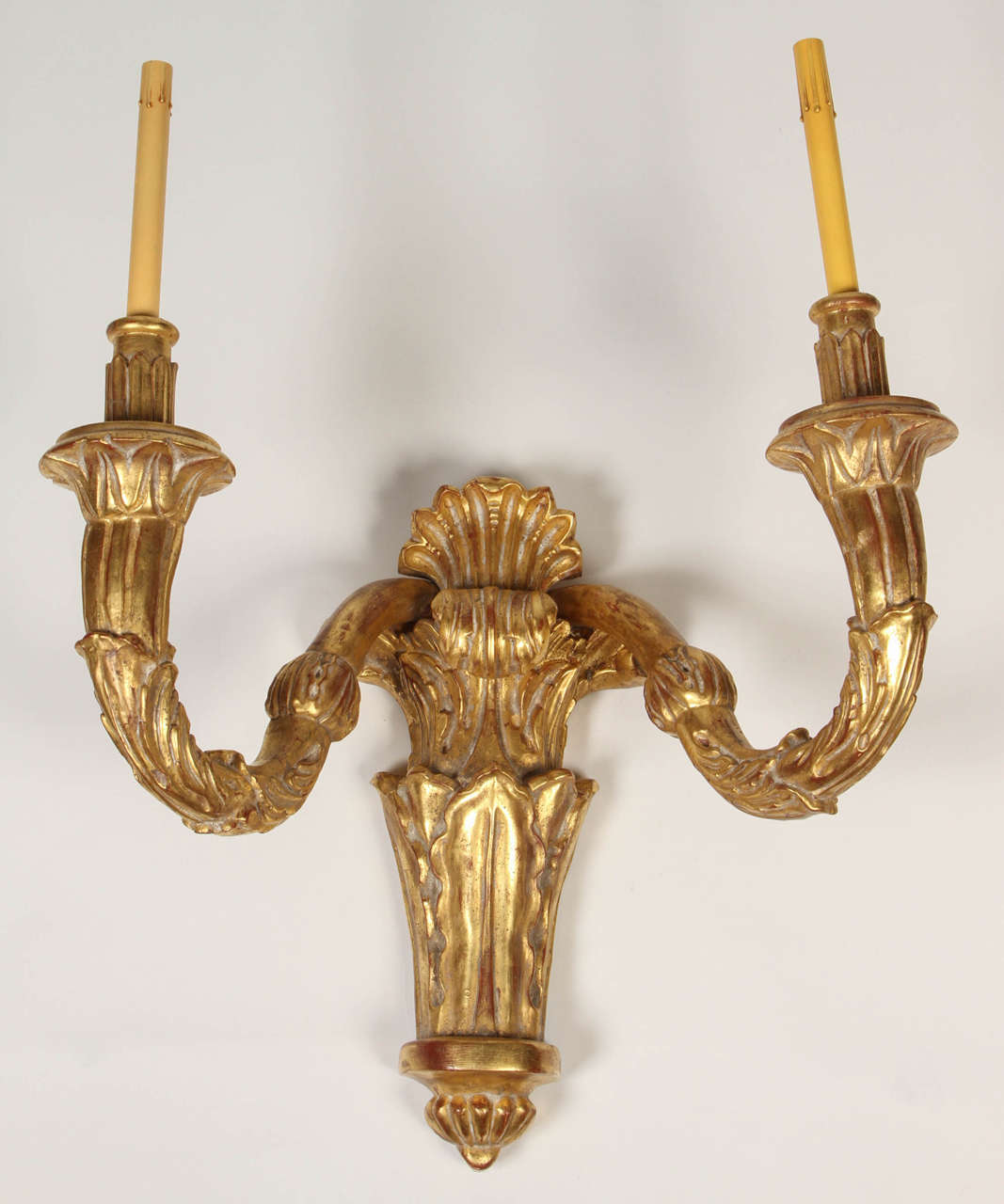 This is a magnificently large set of four giltwood wall lights in the Louis XVI style. Each featuring two arms and wonderfully carved details. They would make a dramatic statement placed down a large hallway or used as ambient light in a dining room.