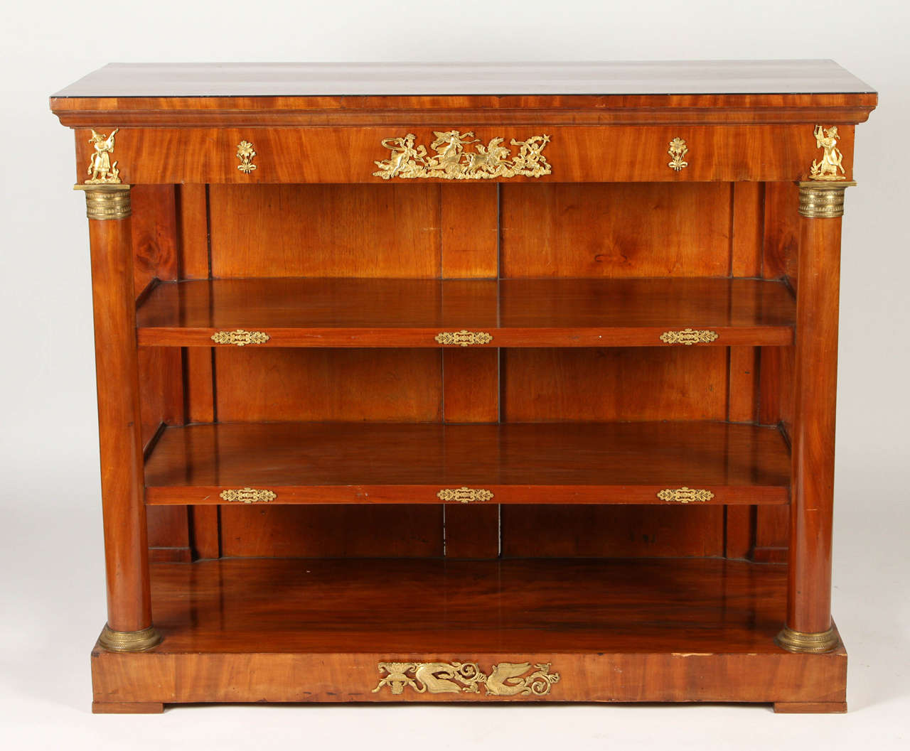 This French Empire console from the early 19th century is made from gorgeous burled amboyna. Round pilasters support two inset shelves and the frieze which is mounted with gilt bronze mounts in chinoiserie figures. This unique piece would be a