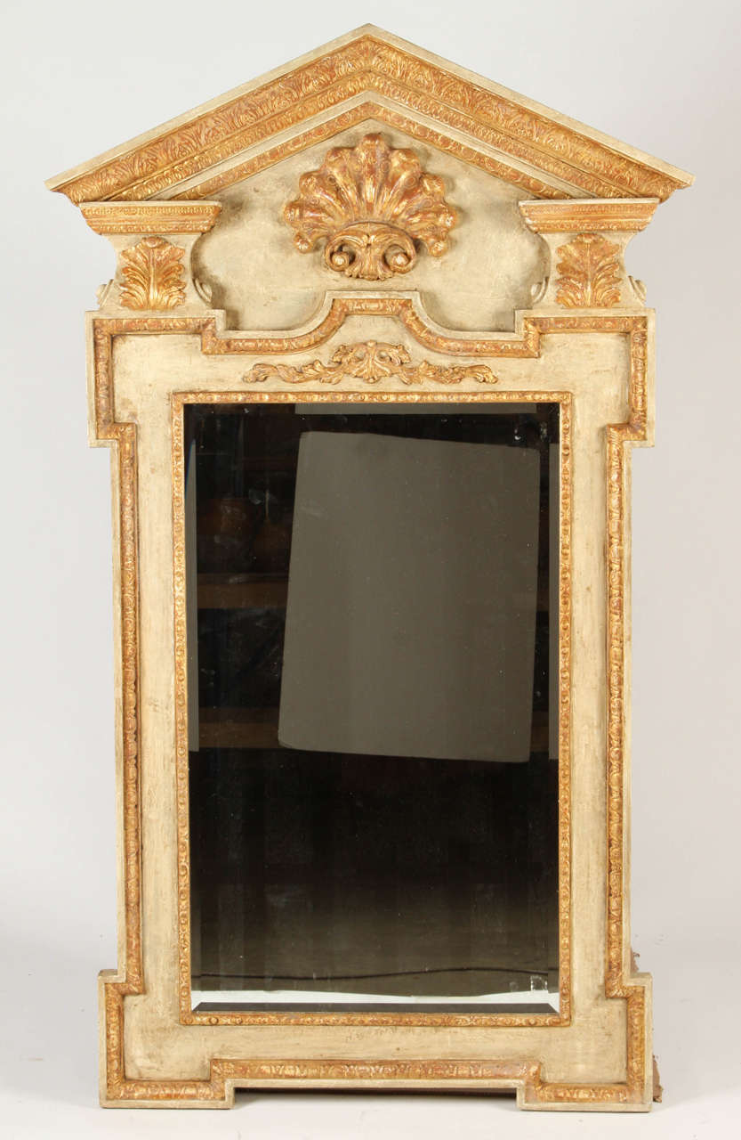 This pier mirror in the George II style is grand in scale and design. The painted and parcel-gilt frame has a grand carved pediment above a shell. 
This mirror would make a strong statement in an entryway over console or used as a dressing mirror.