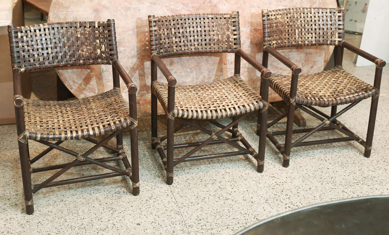 Set of six Antalya laced rawhide arm chairs from McGuire. Manufacturers tag on each chair. Finish on the rawhide has been rubbed to a great patina . Arm height is 25