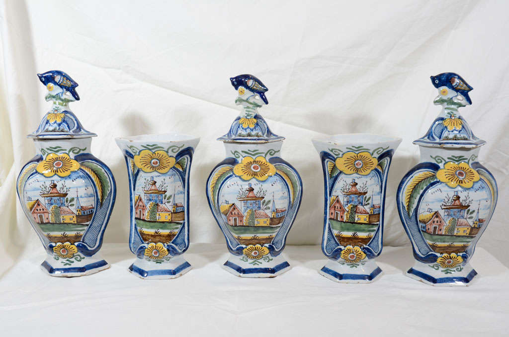 An 18th century garniture of five lovely Dutch delft vases: Three covered and a pair of trumpet vases all showing a brightly colored village scene with homes and a church.
On the bottom of each vase is the mark of the "3 Bells"