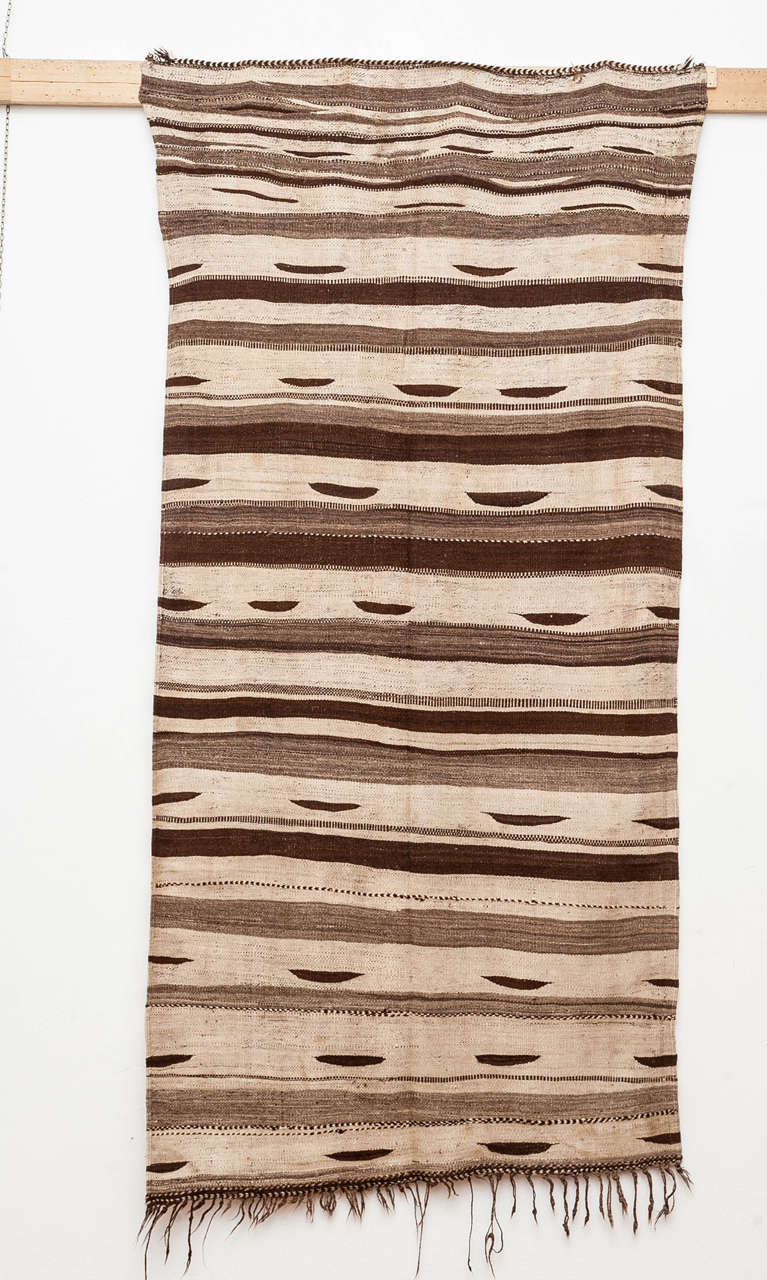 A rare and beautiful flat-weave from the Ourika valley located in the Moroccan High Atlas, distinguished by a mocha palette as well as by a randomly arranged repeat pattern of horizontal stripes of different widths alternated to dark brown 'eyes'.