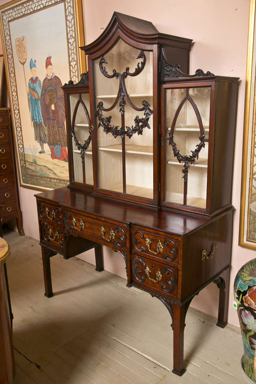This late 18th, early  19th century mahogany display cabinet is made in two parts. The upper glazed section with three opening doors. The tracery of the doors on the glass  is in excellent condition. One glass now does have a small crack.The lower