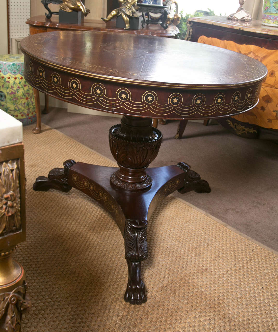 Brass inlays of swirls,  flowers and stars on the top of this unusual table made in India for the English market.  The apron with the same  style stars within  circles and connecting wave forms. Carved central  urn form  pedestal has had a  5 inch