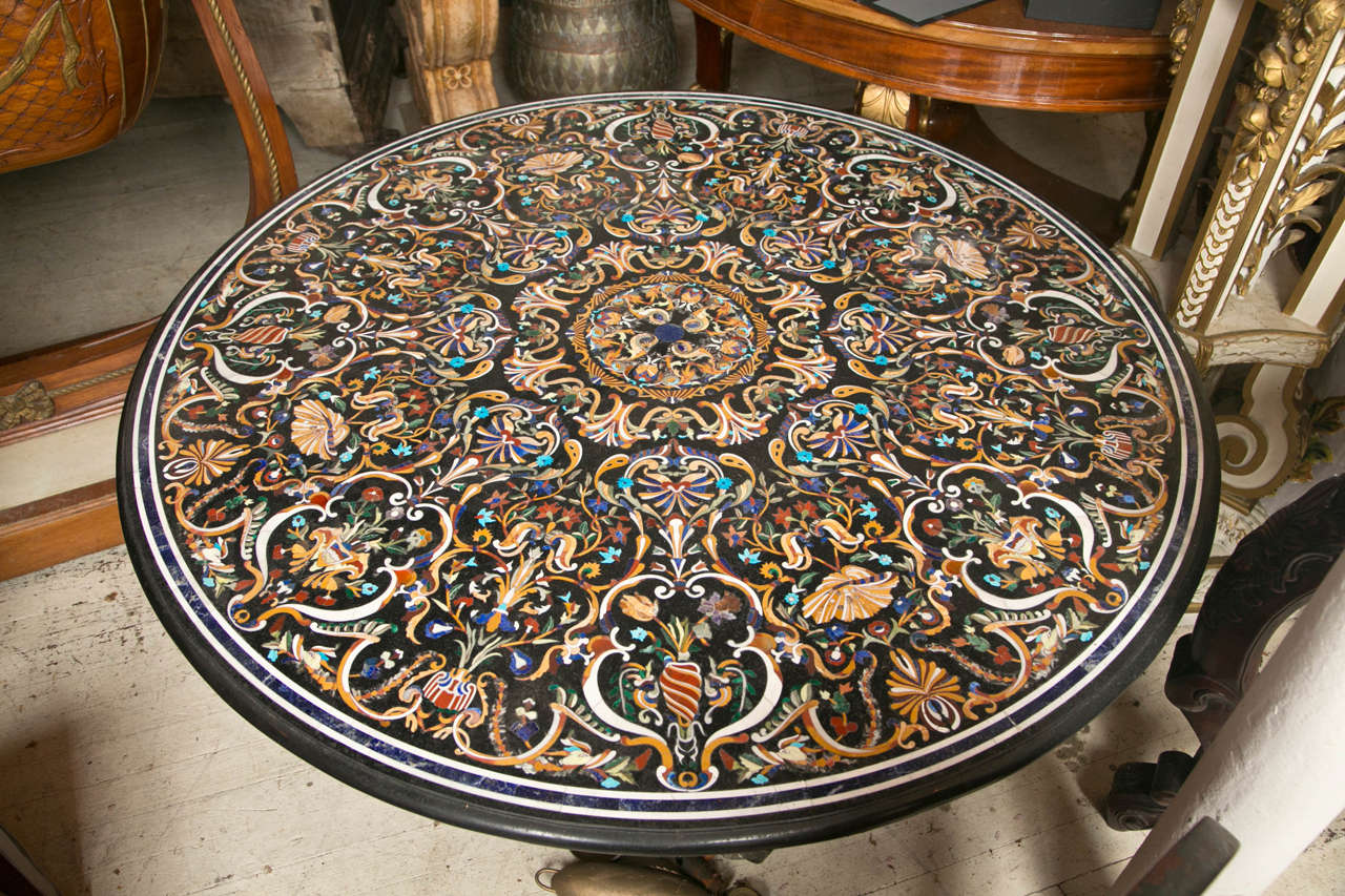 One of the most beautiful pietra dura tops we have seen, this round  top  has black marble  ground with inlays of turquoise, lapis, carnelian,   and other semi precious stones as well as marbles in various colors.  Floral forms, arabesques  within a