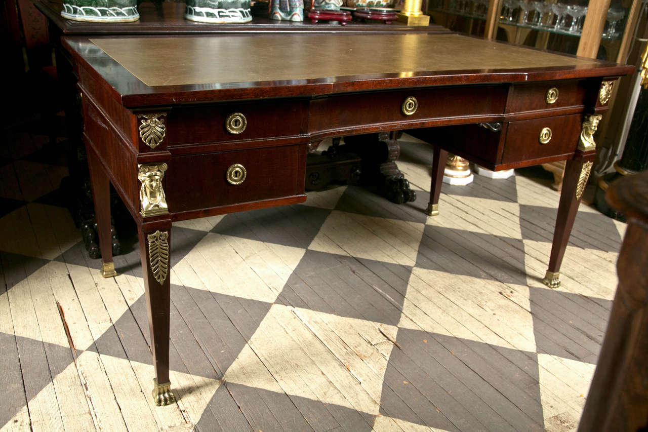 This 20th century writing table has a  green leather top, a  central drawer and flanked  by two drawers on either side. Gilt ring pulls, gilt mounts of acanthus leaves,  female heads and   feet. The back side is finished but has no drawers.