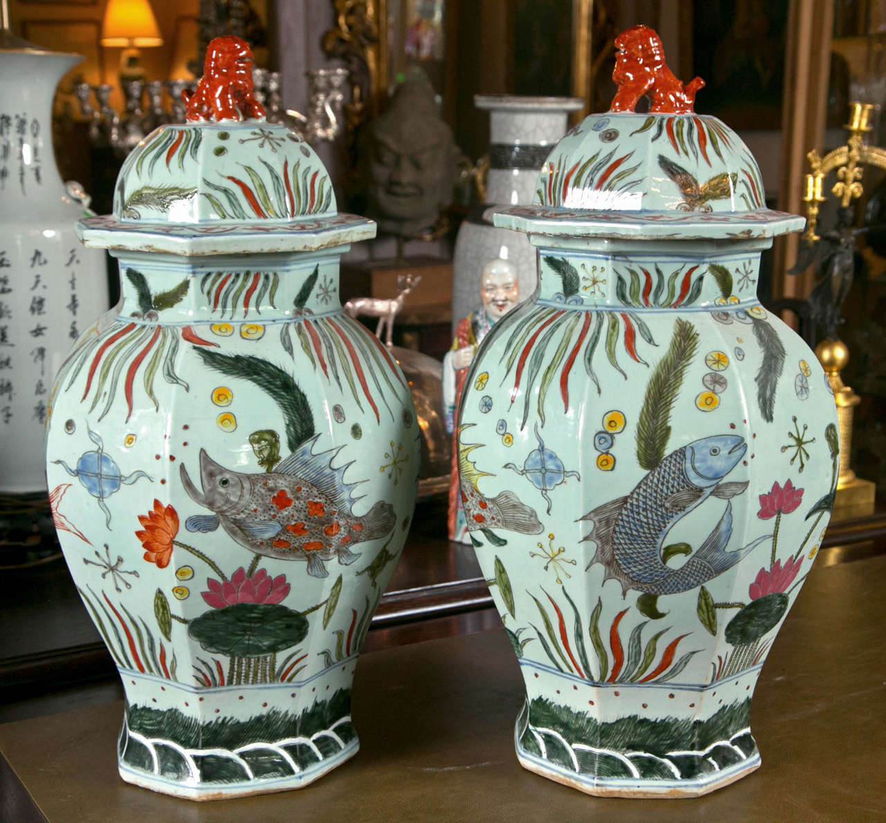 This pair of hand painted porcelain  jars have a palest of celadon background decorated with fish, sea plants and flowers. The lids  have foo dog finials,