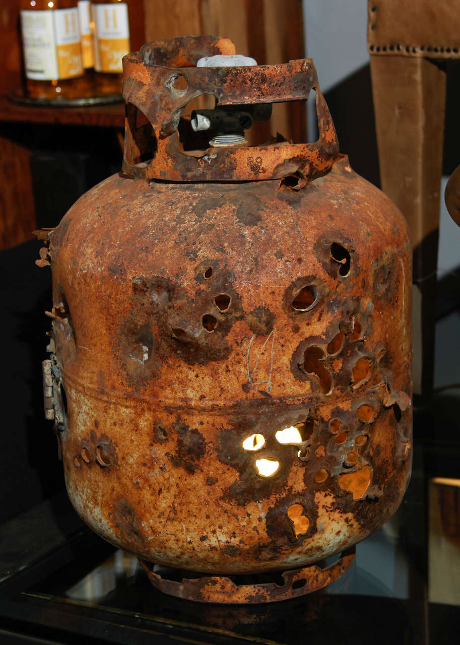 old propane tank that had been used for target practice and left to rust turned into quirky lamp.