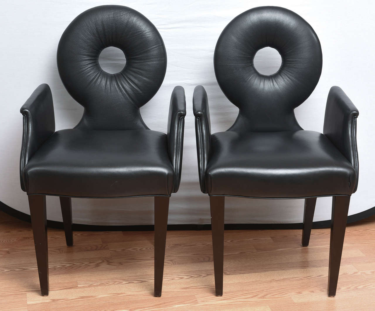 Very chic set of four modern black leather armchairs with an open circle in the center of back.