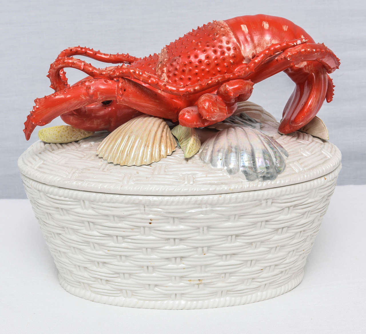 Exquisite white basket weave tureen topped with shells and finely detailed lobster.