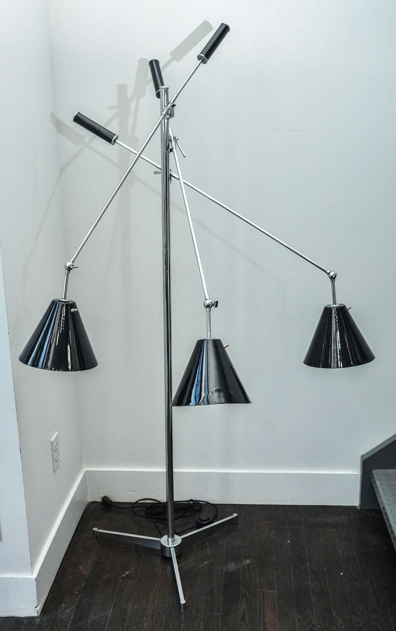 "Triennale" floor lamp designed and stamped Angelo Lelli for Arredoluce.
Chrome plated brass with black enameled shades and arm handles.
Single chrome lamp pole secured in tripod floor base, with three adjustable
and articulating arms. 