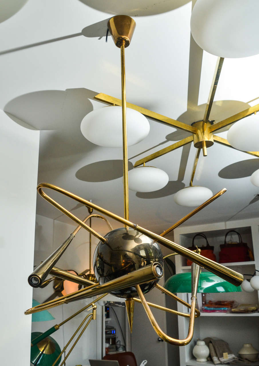 Our solar system inspired this chandelier produced in the 1950's by Stilnovo. Four brass bent arms emanate from the center brass sphere creating the illusion of planets around the sun.  All original brass this fixture has been rewired for