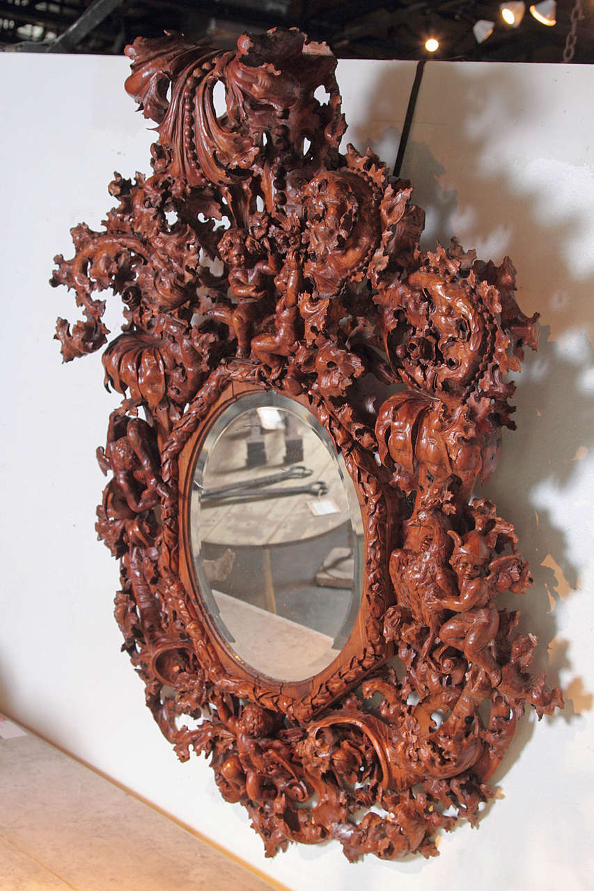 This stunning and large antique Baroque Venetian mirror has a vigorously, hand-carved, wooden surround of jaggedly lobed acanthus leaves, oak leaves, cherubs, and birds. The beveled, inner mirror is within an octagonal molded border of reed and