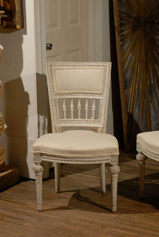 A pair of Swedish late 18th century period Gustavian side chairs with upholstered seats. This pair of Swedish chairs features a nicely carved and upholstered back, rosettes on the knees as well as tapered and fluted legs, they have their original