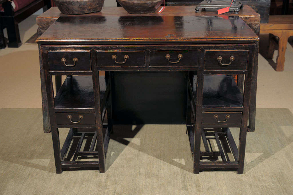 Antique elmwood Chinese black desk with 6 drawers and lattice shelves from Wunan province.  Original lacquer and hardware. 19th cen.