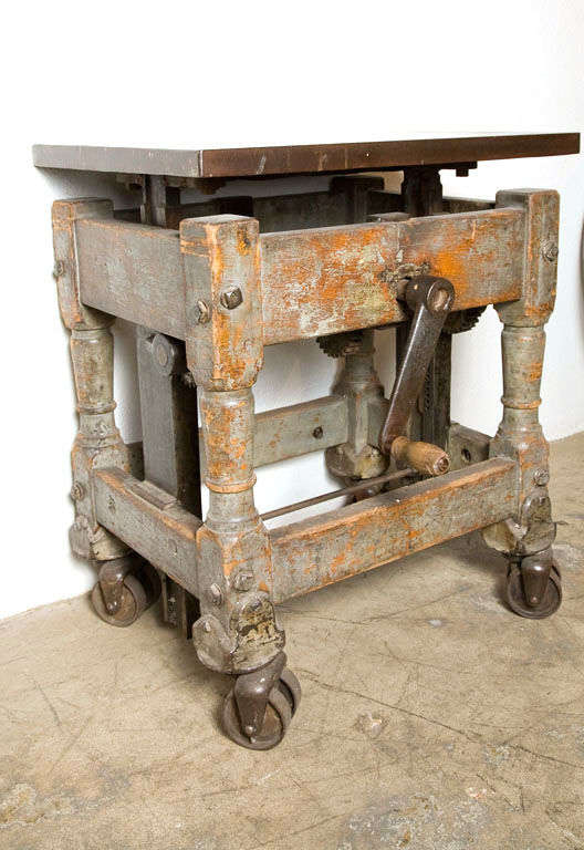 Beautiful craftsmanship! An unusual industrial crank table with fantastic turned wooden legs and a thick floating iron top.
